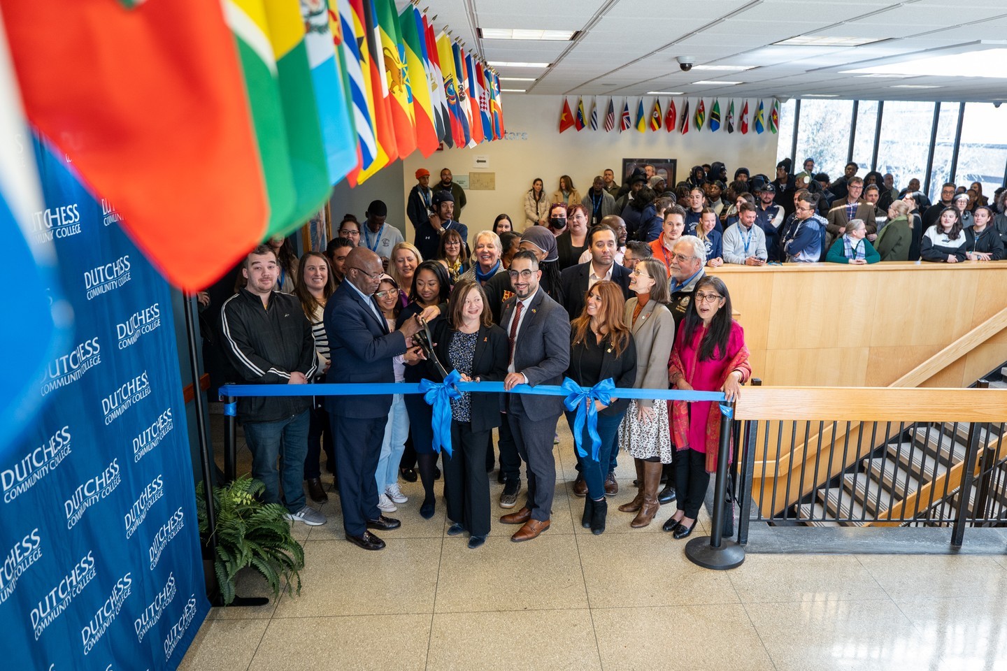 DCC president cutting ribbon to international flag display